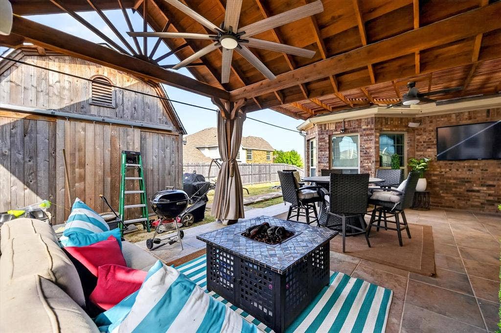 902 Nikki Drive, Cedar Hill, TX 75104 Covered patio with exposed wood beam ceiling, ceiling fans, tile flooring, and a brick exterior wall