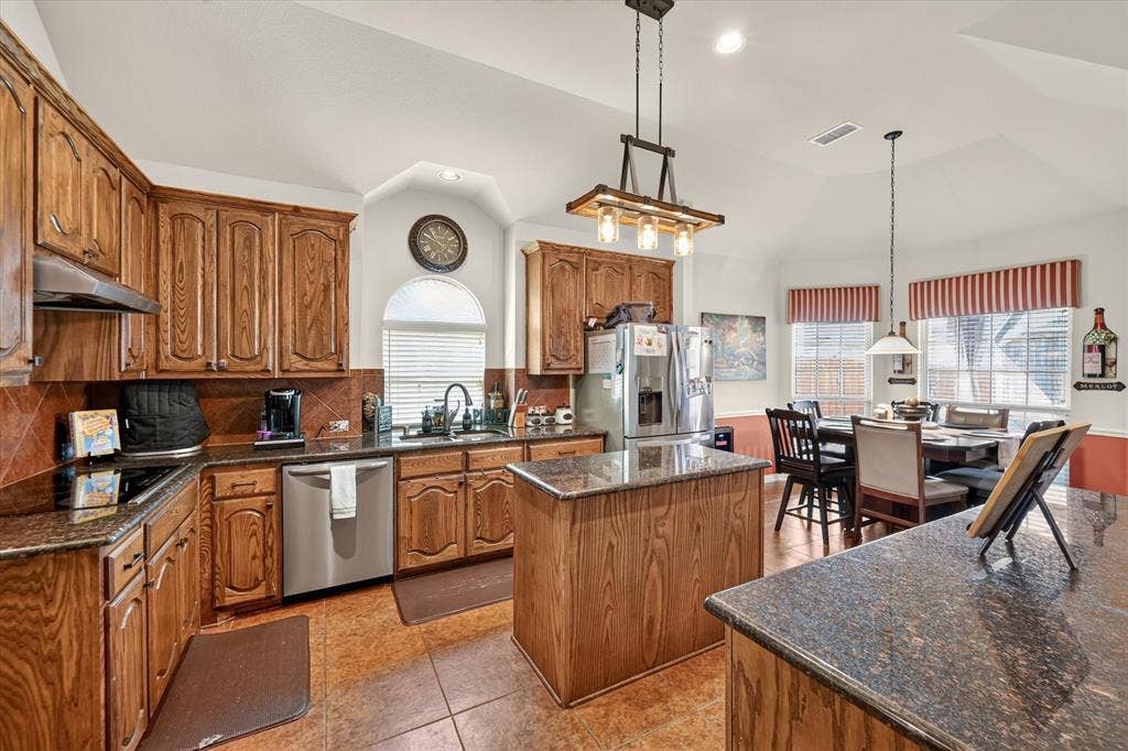 902 Nikki Drive, Cedar Hill, TX 75104 Kitchen featuring wood cabinetry, dark countertops, a central island, and stainless steel appliances
