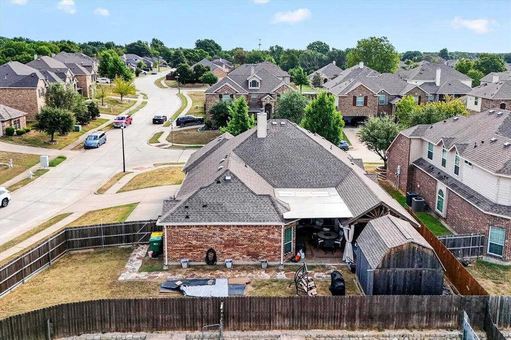 902 Nikki Drive, Cedar Hill, TX 75104 Red brick exterior with a dark shingle roof, featuring a covered patio, a detached shed, and a fenced backyard