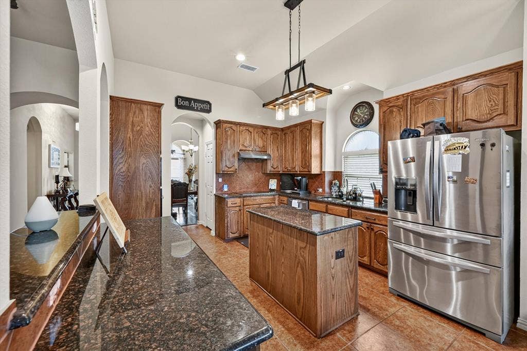 902 Nikki Drive, Cedar Hill, TX 75104 Kitchen featuring wood cabinetry, stainless steel appliances, a center island, and dark speckled countertops