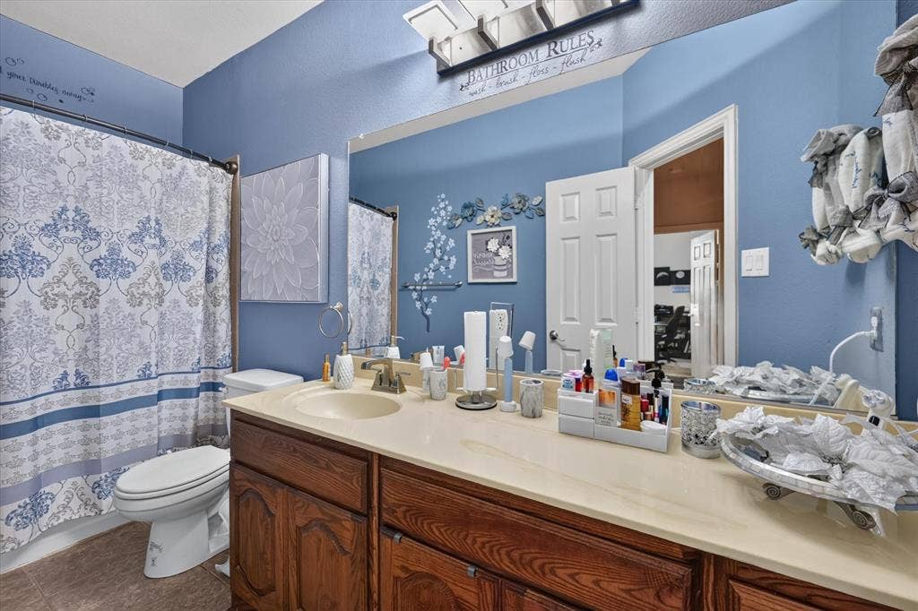 902 Nikki Drive, Cedar Hill, TX 75104 Single vanity with an integrated sink, wood-finish cabinetry, and a full-width wall mirror
