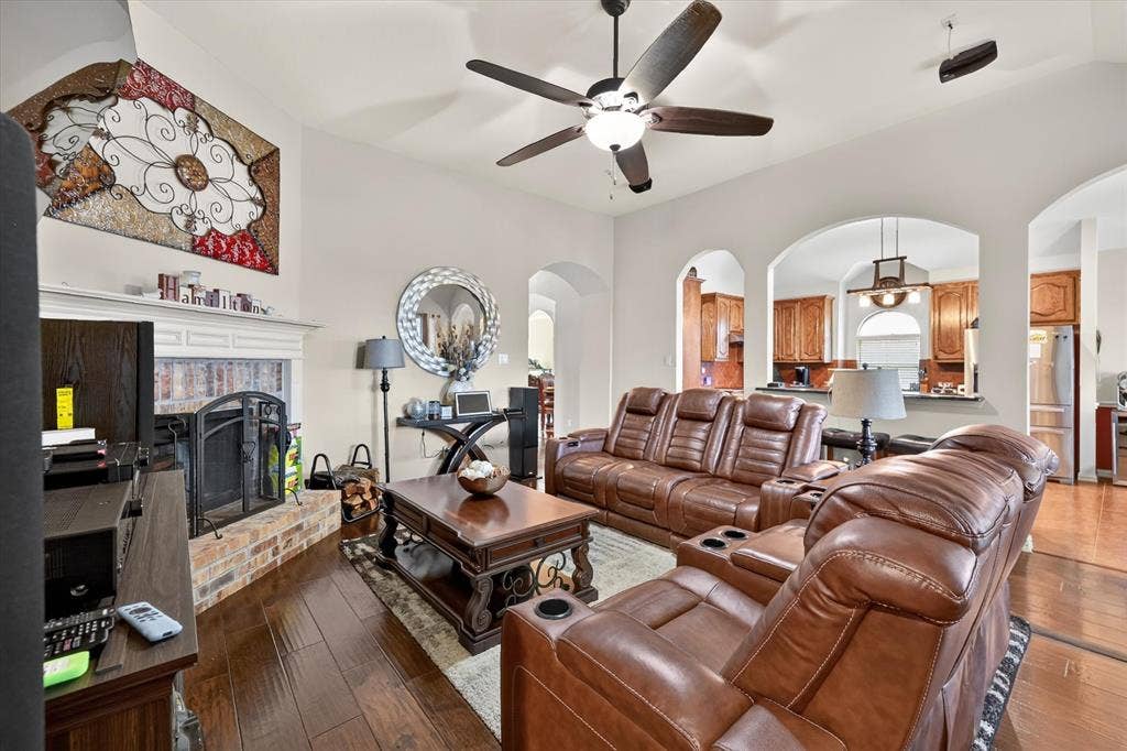 902 Nikki Drive, Cedar Hill, TX 75104 Spacious living area featuring wood-finish flooring, a ceiling fan, and a brick-surround fireplace with a white mantel