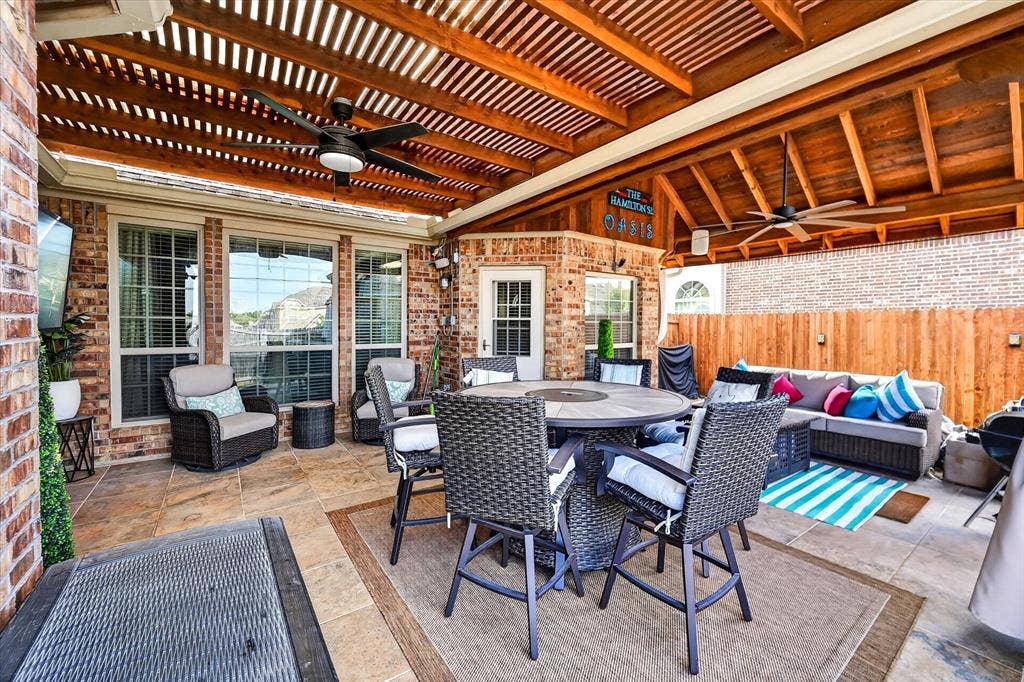 902 Nikki Drive, Cedar Hill, TX 75104 Expansive covered patio featuring a wood-slat ceiling, dual ceiling fans, brick exterior, and a privacy fence