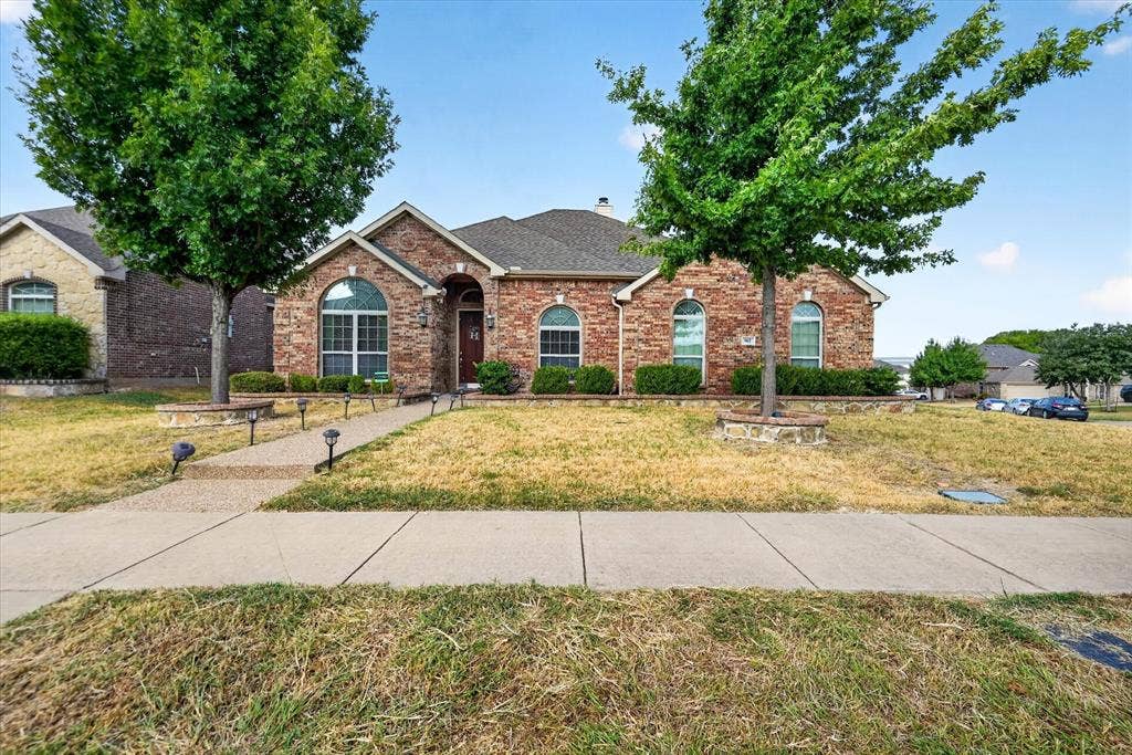 902 Nikki Drive, Cedar Hill, TX 75104 Brick facade with arched windows, mature trees, and a front walk with landscape lighting