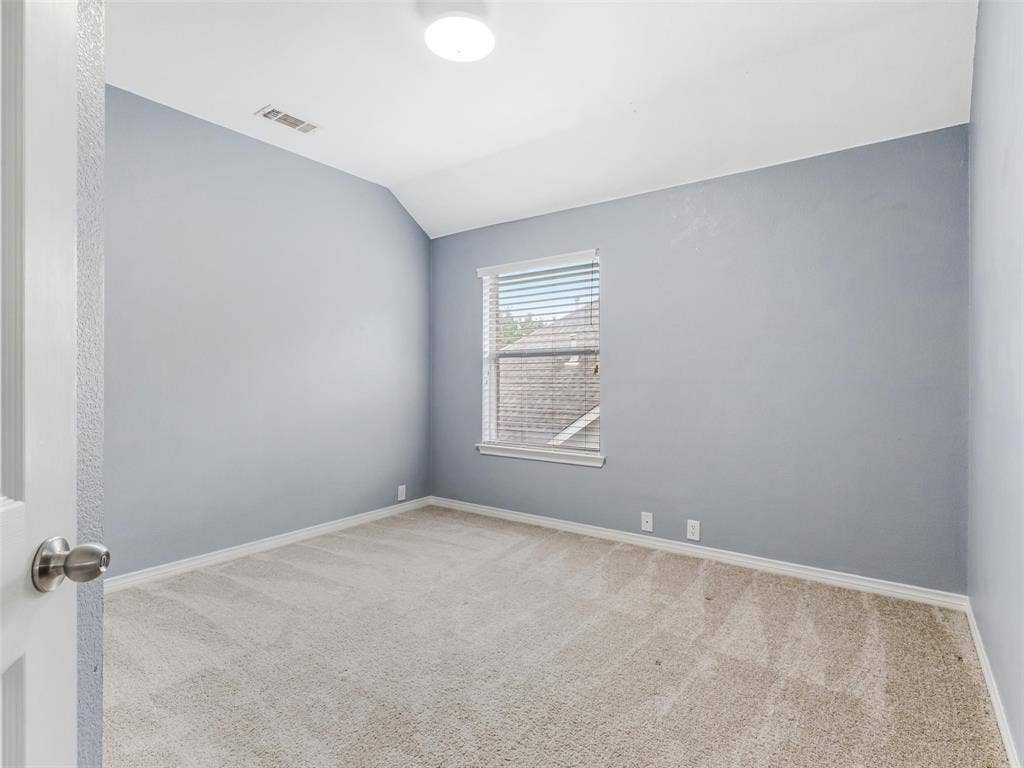 7419 Ravenhill Drive, Frisco, TX 75035 Vaulted ceiling with flush-mount lighting, neutral carpeting, and a window with blinds