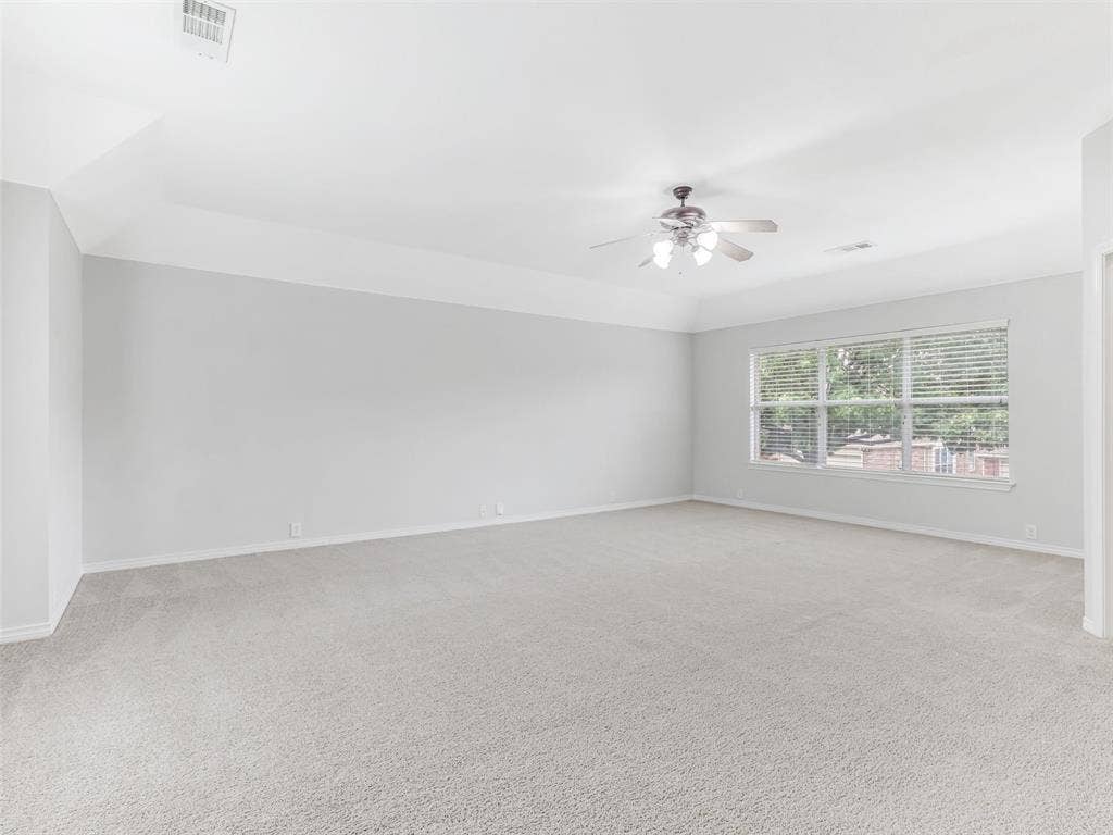 7419 Ravenhill Drive, Frisco, TX 75035 Spacious room featuring neutral carpeting, tray ceiling, a ceiling fan with integrated lighting, and a large window with blinds