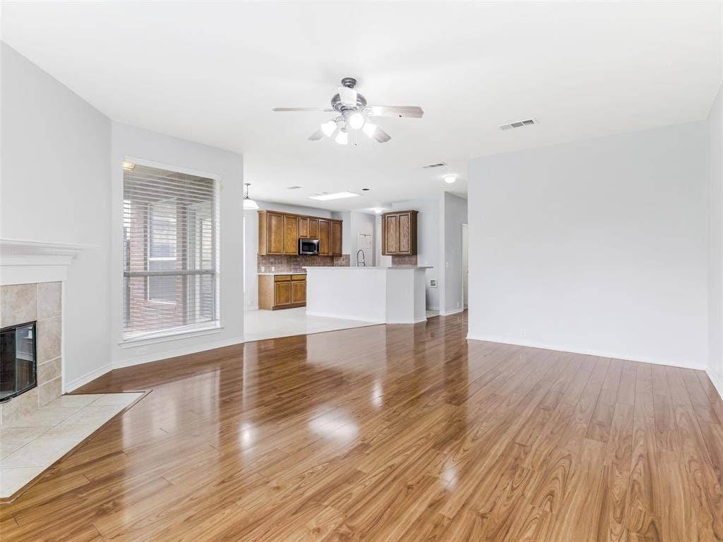 7419 Ravenhill Drive, Frisco, TX 75035 Spacious living area featuring wood-finish flooring, a tiled fireplace, and a ceiling fan