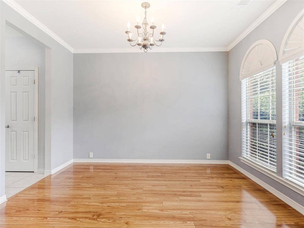 7419 Ravenhill Drive, Frisco, TX 75035 Wood-finish flooring with a high-gloss finish, crown molding, arched transom windows, and an elegant chandelier