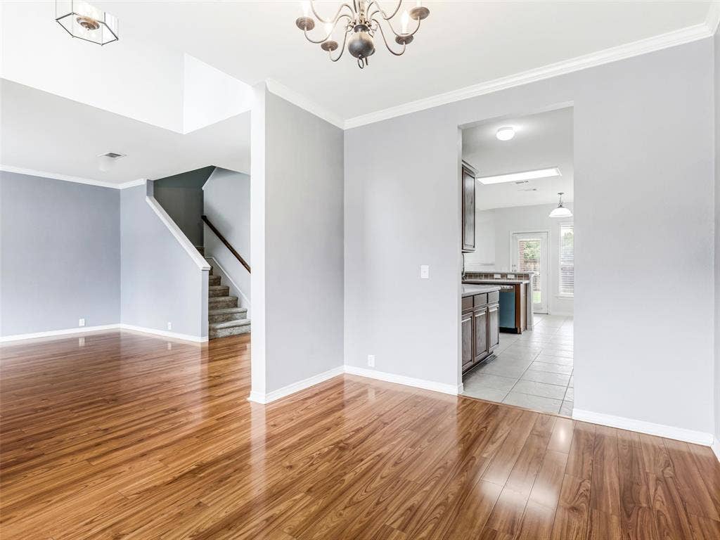 7419 Ravenhill Drive, Frisco, TX 75035 Wood-finish flooring, staircase with carpeted treads and wood handrail, crown molding, chandelier, and a recessed ceiling light fixture