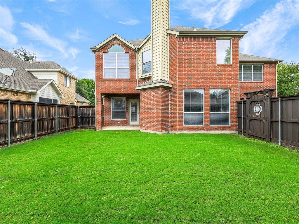 7419 Ravenhill Drive, Frisco, TX 75035 Brick exterior with multiple windows, arched window feature, and a privacy fence