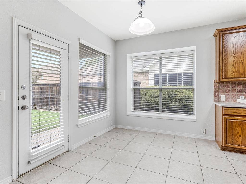 7419 Ravenhill Drive, Frisco, TX 75035 Neutral-toned square tile flooring, multiple windows, and a glass-paneled exterior door provide natural illumination