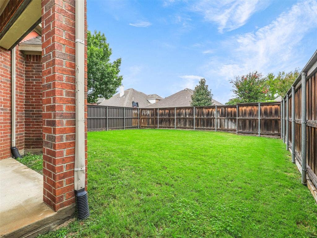 7419 Ravenhill Drive, Frisco, TX 75035 Expansive green lawn enclosed by a durable wood privacy fence