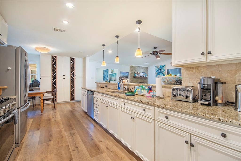 4074 Cedar Bayou Drive, Dallas, TX 75244 Kitchen featuring light wood-finish flooring, white cabinetry with dark hardware, a stone backsplash, and recessed lighting