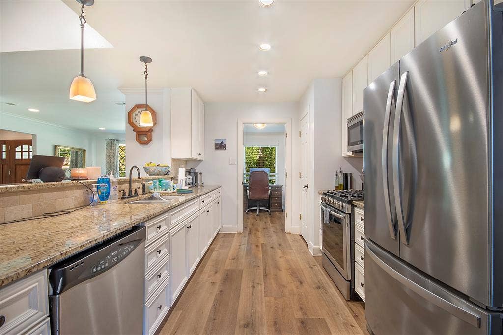 4074 Cedar Bayou Drive, Dallas, TX 75244 Kitchen featuring wood-finish flooring, white cabinetry, a stainless steel refrigerator, stainless steel range, and a granite-style countertop