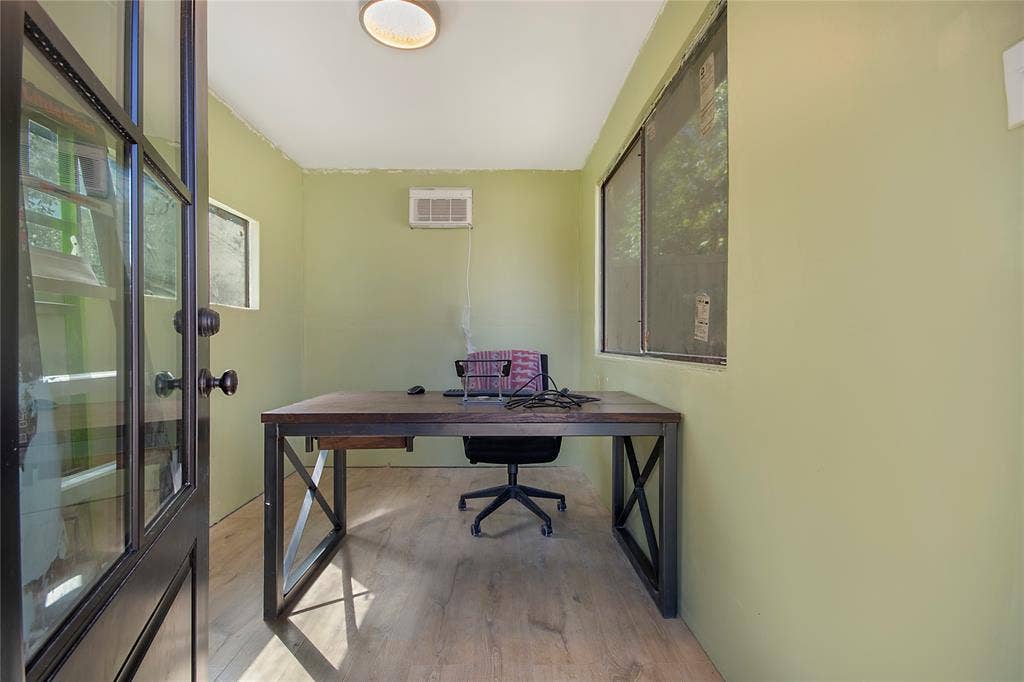 4074 Cedar Bayou Drive, Dallas, TX 75244 Dedicated home office featuring a sturdy wood-finish desk with X-frame styling, wood-finish flooring, and abundant natural light from dual glass doors and windows