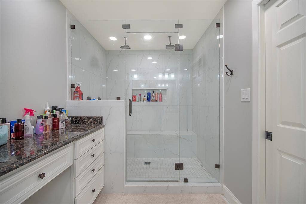4074 Cedar Bayou Drive, Dallas, TX 75244 Walk-in shower with clear glass enclosure, white tile walls, and a built-in bench