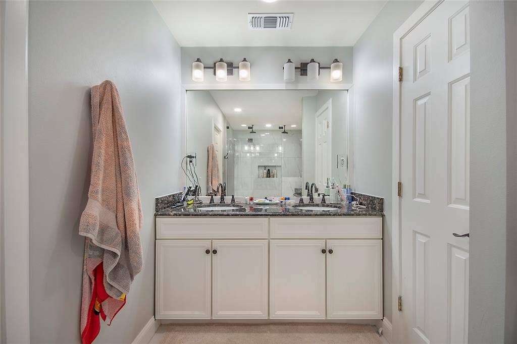 4074 Cedar Bayou Drive, Dallas, TX 75244 Double vanity with a dark countertop, undermount sinks, and wall-mounted light fixtures