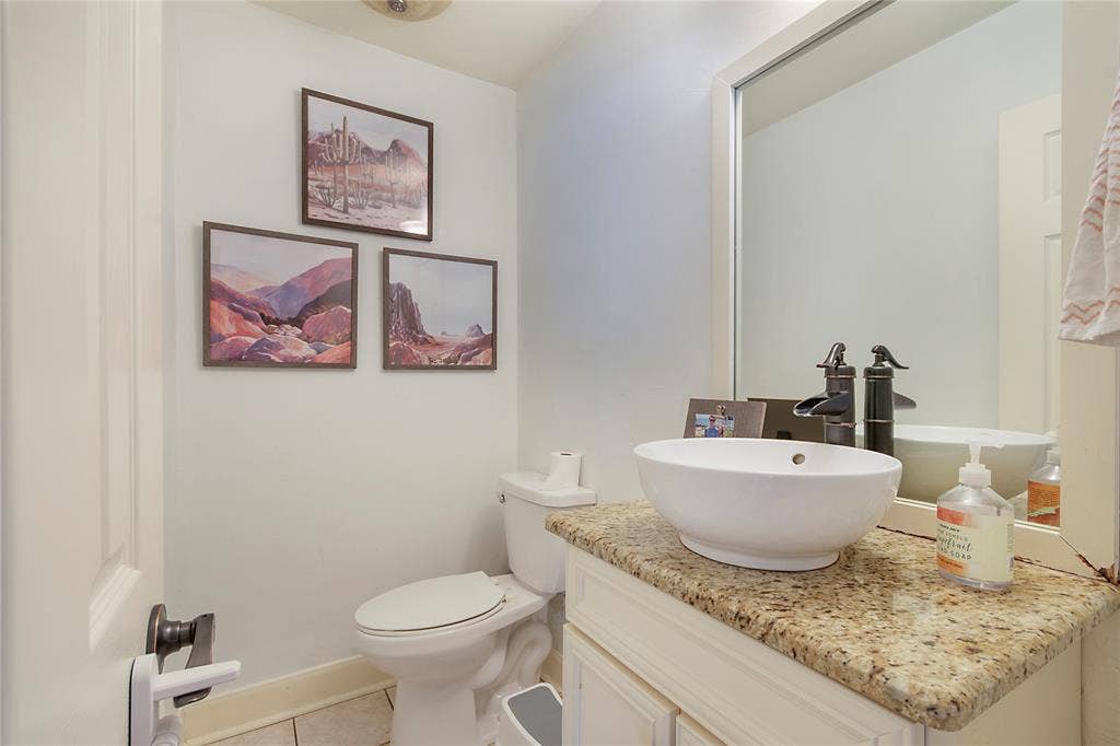 4074 Cedar Bayou Drive, Dallas, TX 75244 Granite countertop, vessel sink, oil-rubbed bronze faucet, built-in vanity cabinetry, and tile flooring