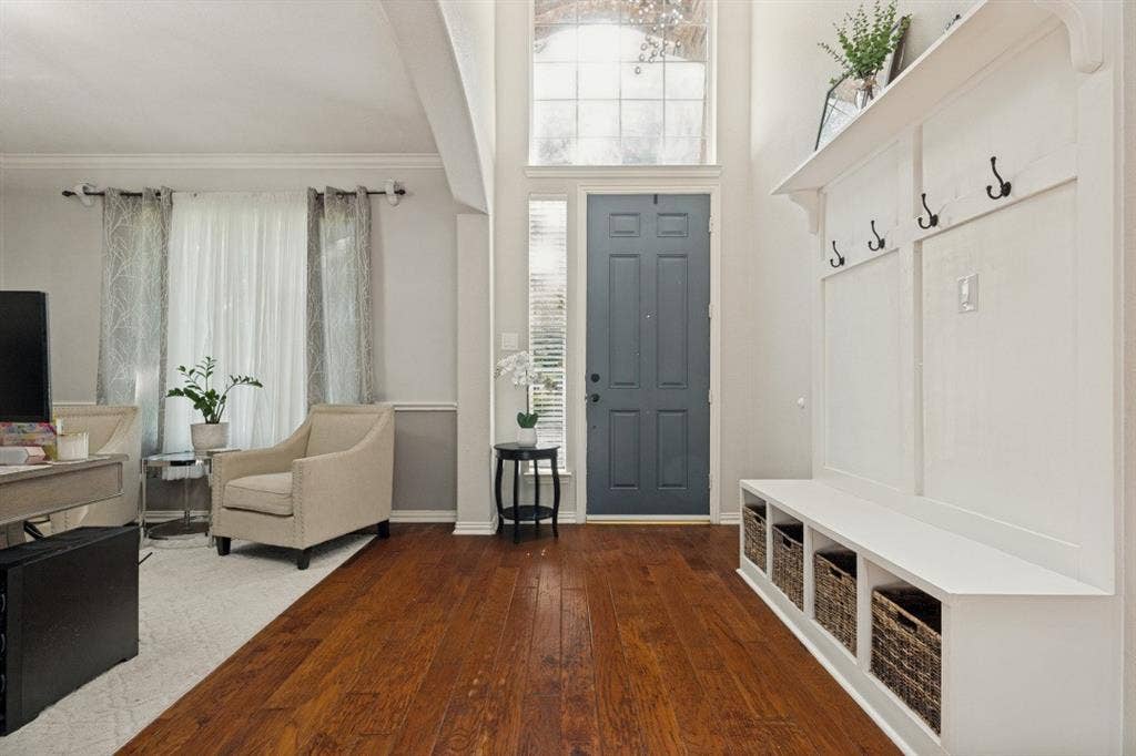 Bright, welcoming foyer featuring abundant natural light, a decorative chandelier, and a custom built-in drop zone for everyday convenience.