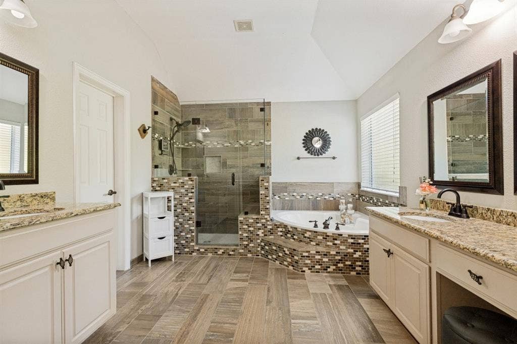 Spa-inspired primary bath with separate vanities, a soaking tub, separate shower, and ample storage.