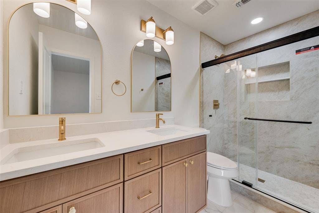 Primary bath features an extended vanity and glass-enclosed shower.