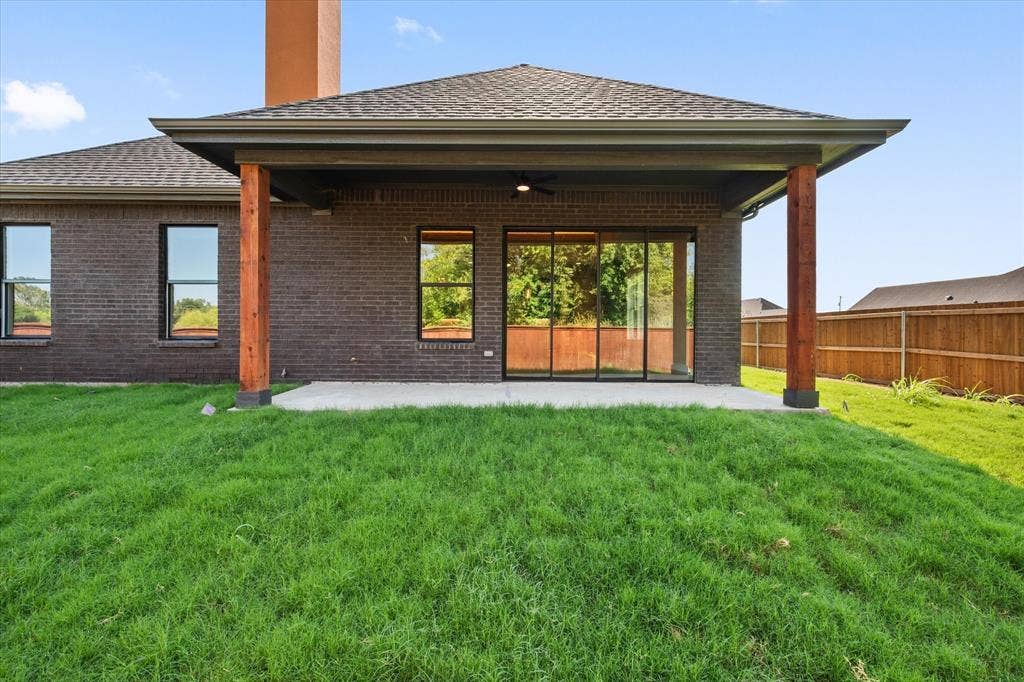 Covered patio with a concrete slab, dark brick exterior, and a wood support beam