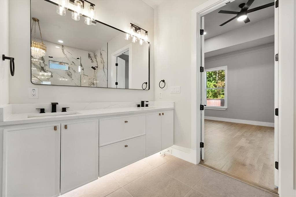 Dual vanity with white cabinetry, matte black hardware, and a large framed mirror