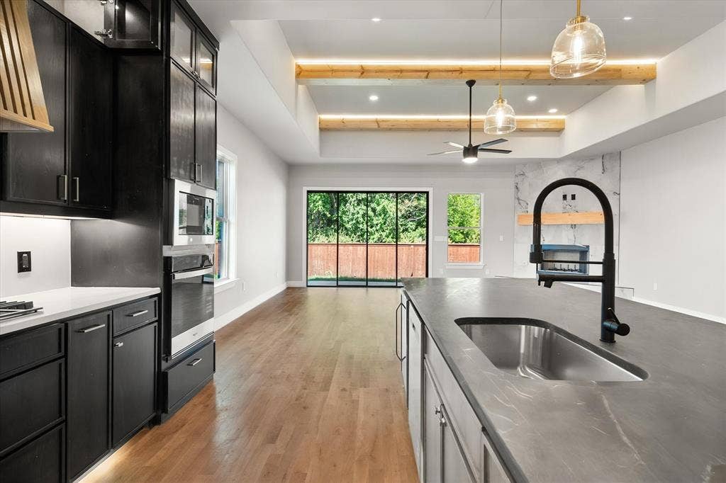 Modern kitchen with dark cabinetry, integrated appliances, and a central island featuring an undermount sink
