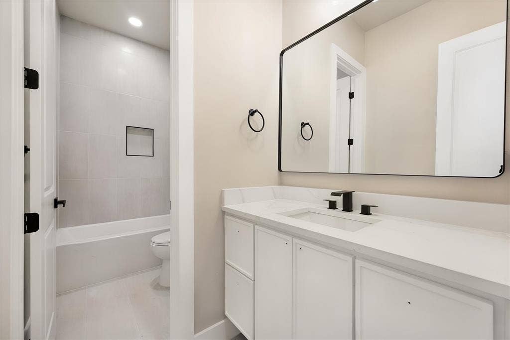 White vanity with a solid surface countertop, undermount sink, and matte black fixtures