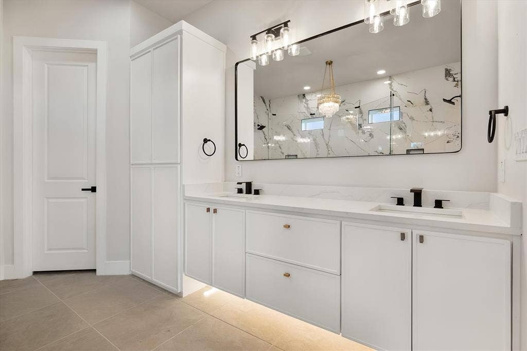 Double vanity with integrated sinks, white cabinetry, undermount lighting, and matte black fixtures