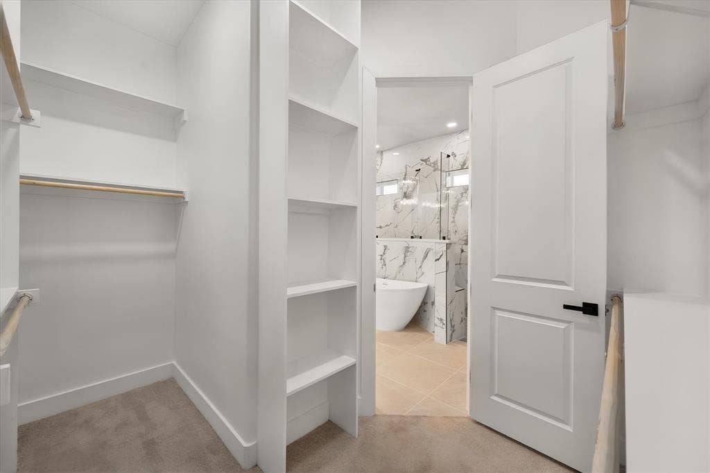 Walk-in closet with built-in shelving, hanging rods, and carpet flooring