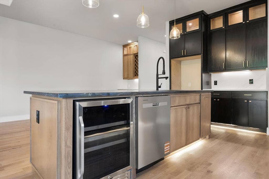 Expansive kitchen island with a built-in beverage refrigerator, stainless steel dishwasher, and a matte black faucet