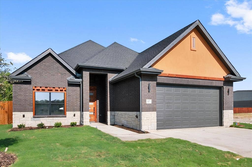 Dark brick exterior with stone accents, a deep gray garage door, a prominent front entry, and a wood-framed window