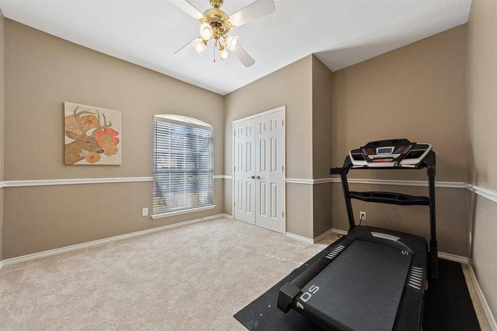 Arched window with blinds, dual paneled doors, ceiling fan with integrated lighting, and crown molding
