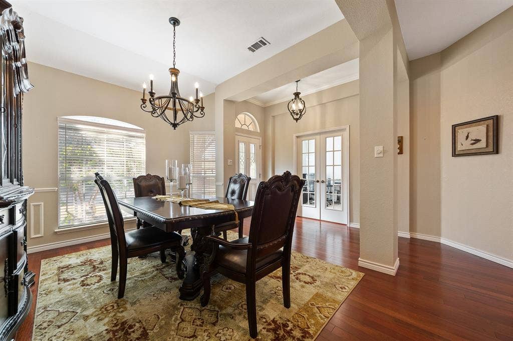 Wood-finish flooring, a decorative chandelier, and French doors with transom window