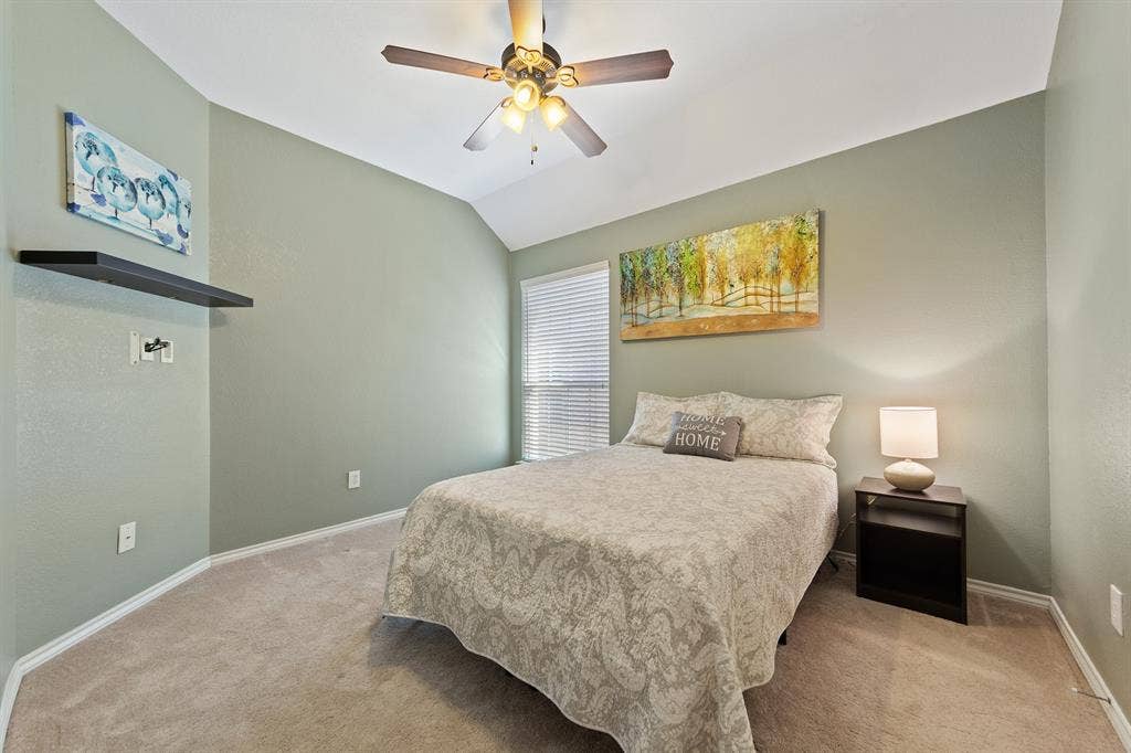 Vaulted ceiling with an attached ceiling fan, wall-to-wall carpeting, and a window with blinds
