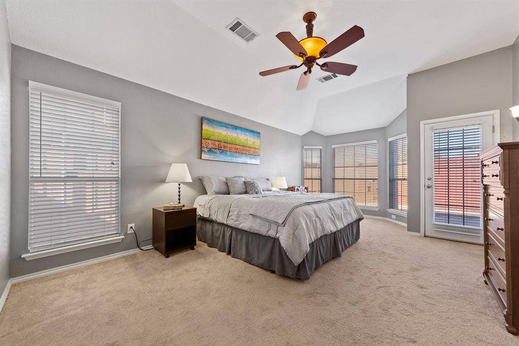 Tray ceiling with a ceiling fan light fixture, multiple windows with blinds, and a glass-paneled door