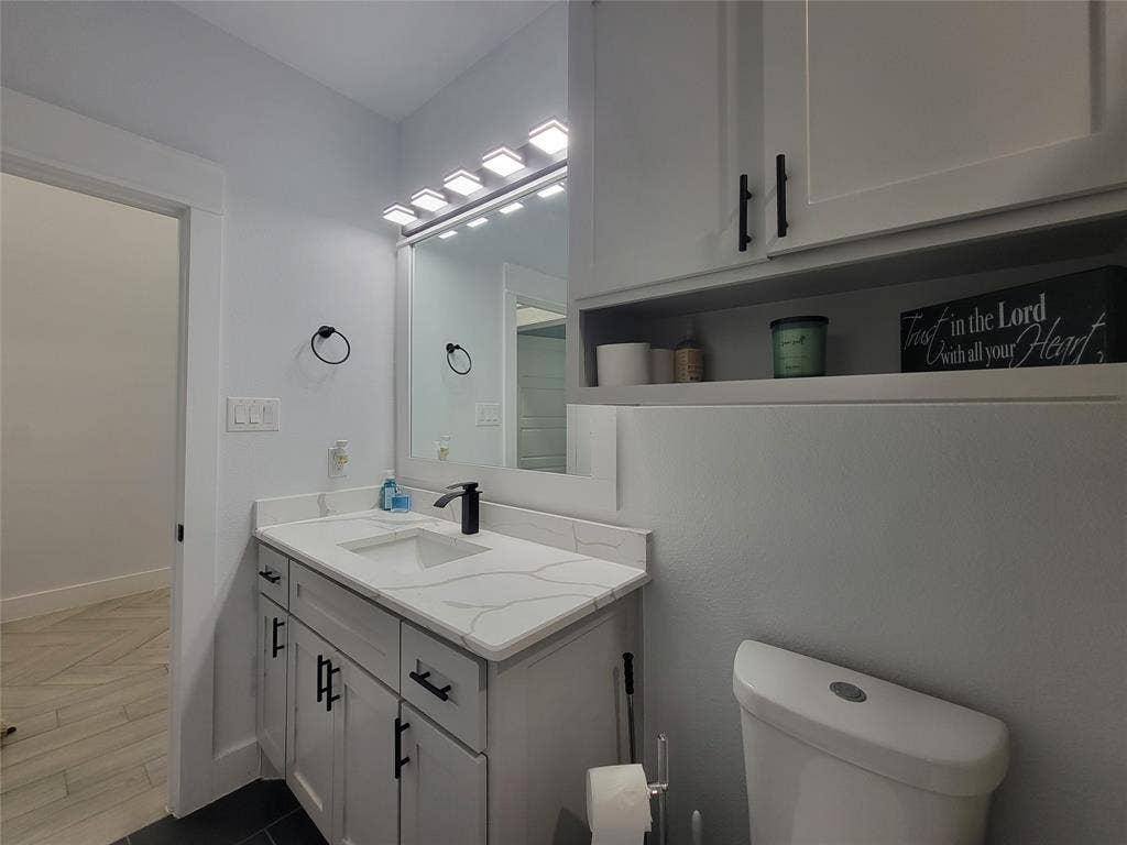 3207 NW 30th Street, Fort Worth, TX 76106 Vanity with a white countertop and integrated sink, black faucet, and white cabinetry