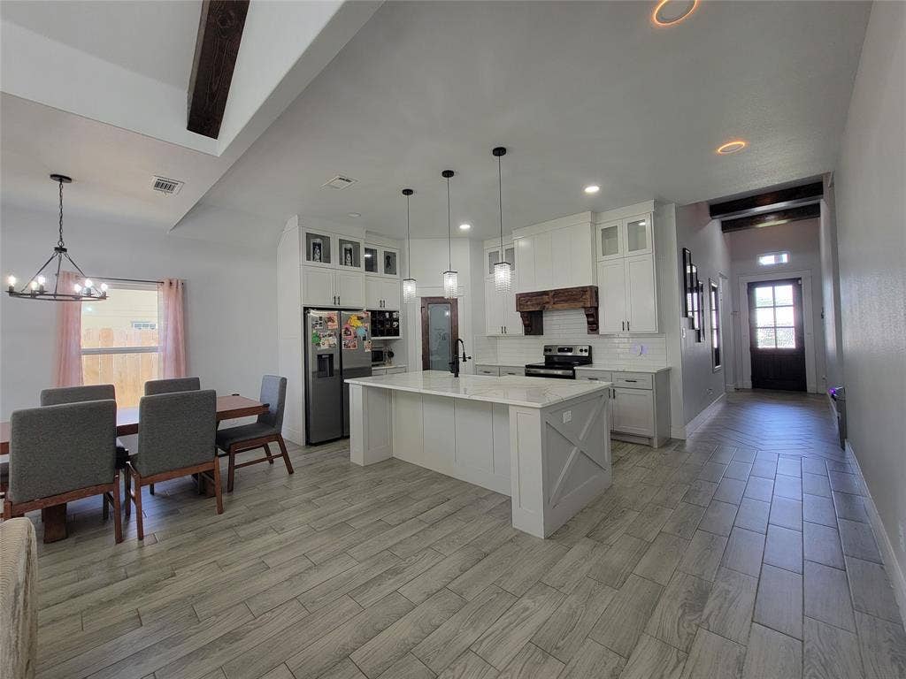 3207 NW 30th Street, Fort Worth, TX 76106 Kitchen featuring a central island with a stone countertop, white shaker cabinetry, and stainless-steel appliances