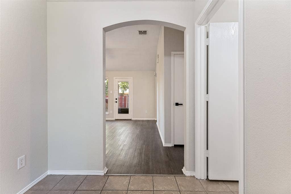 4545 Grainland Court, Fort Worth, TX 76179 Archway entry to interior space, featuring tile flooring transitioning to wood-finish flooring, and a white door with matte black hardware