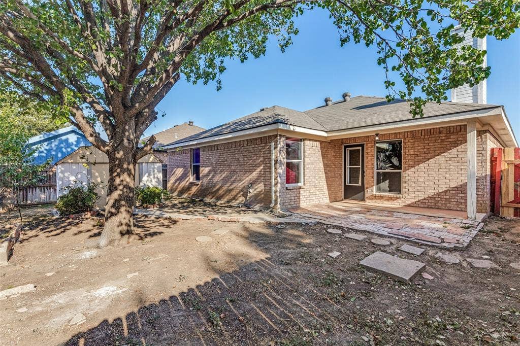 4545 Grainland Court, Fort Worth, TX 76179 Brick exterior with covered patio, wood fencing, and a detached storage shed