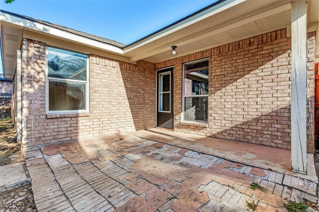 4545 Grainland Court, Fort Worth, TX 76179 Covered patio with a brick veneer exterior, multiple windows, and exterior lighting