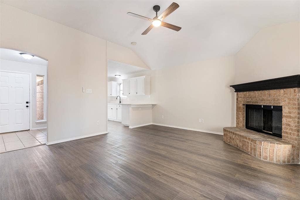 4545 Grainland Court, Fort Worth, TX 76179 Vaulted ceiling, wood-finish flooring, brick fireplace with mantel, ceiling fan, and white cabinetry