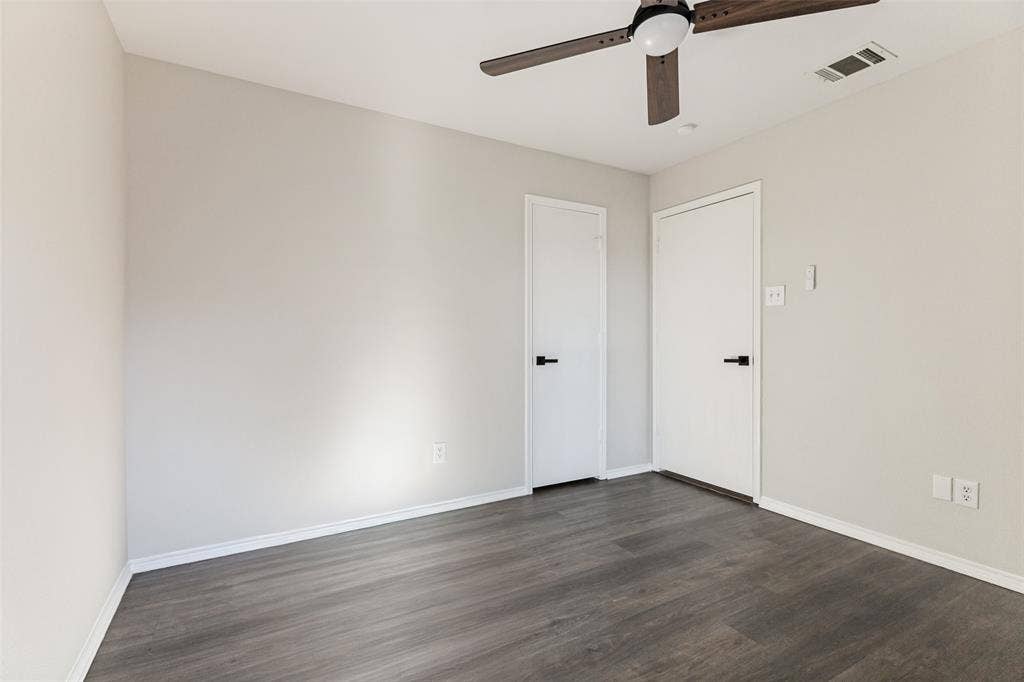 4545 Grainland Court, Fort Worth, TX 76179 Grey wood-finish flooring, light grey walls, white doors with matte black hardware, and a ceiling fan with dark wood-finish blades