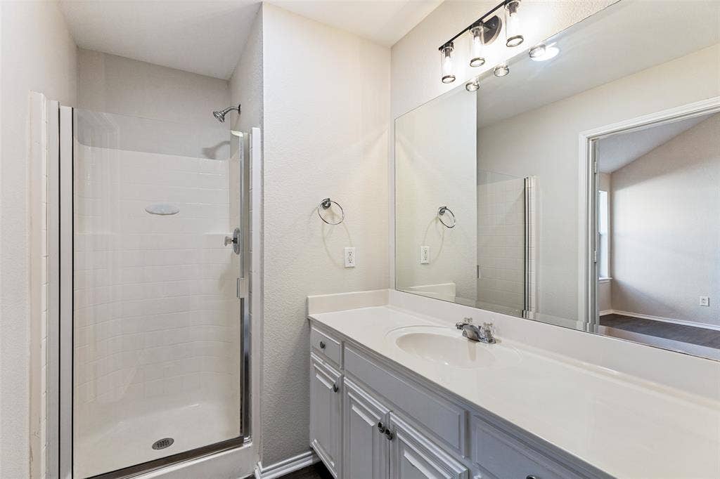 4545 Grainland Court, Fort Worth, TX 76179 White vanity with integrated sink, chrome faucet, and expansive mirror