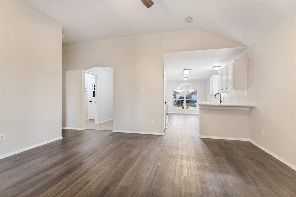 4545 Grainland Court, Fort Worth, TX 76179 Vaulted ceiling, wood-finish flooring, arched doorway, kitchen pass-through, and a ceiling fan