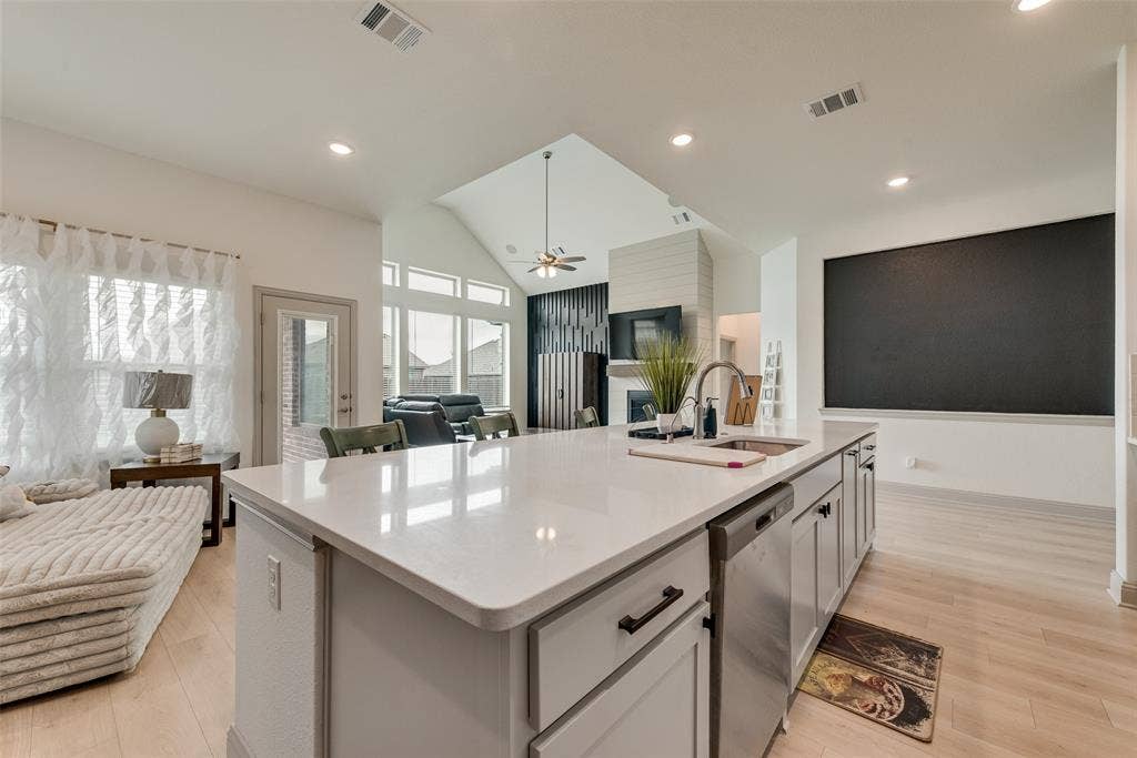 107 White Sands Lane, Forney, TX 75126 Kitchen island with a stainless steel sink, pull-down faucet, integrated dishwasher, and light-toned countertops