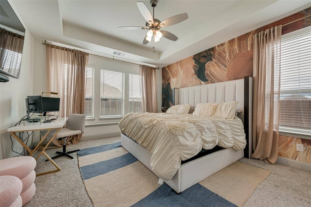 107 White Sands Lane, Forney, TX 75126 Primary bedroom with a tray ceiling, ceiling fan, multiple large windows, and carpeted flooring