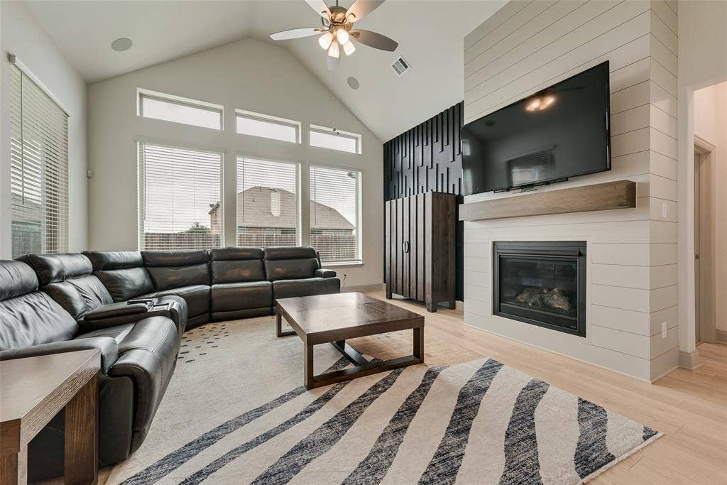 107 White Sands Lane, Forney, TX 75126 Vaulted ceiling with a ceiling fan, fireplace with a wood mantel, wood-finish flooring, and expansive windows