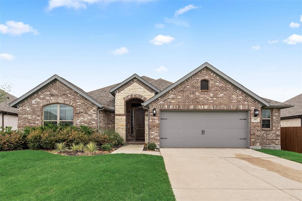 107 White Sands Lane, Forney, TX 75126 Brick exterior with an arched entryway, attached two-car garage, and established landscaping